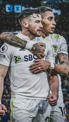 two soccer players hugging each other in the rain