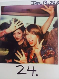 two girls with their hands in the air and one is holding her hand up while the other