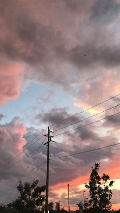 the clouds are pink and blue as the sun sets in the sky above some power lines