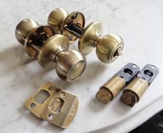 three brass door knobs and two black handles on a marble table