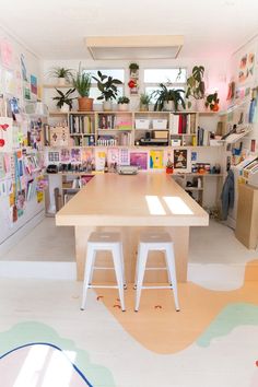 two stools sit in front of a table with bookshelves on the wall