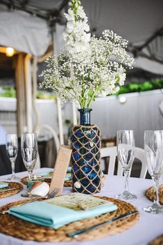 a table set with place settings and flowers in a vase on top of the table