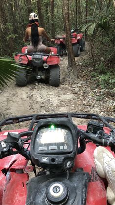 two people riding four wheelers in the woods