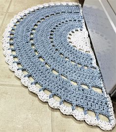 a blue and white crocheted rug sitting on the floor next to an appliance