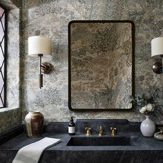 a bathroom sink sitting under a large mirror next to a wall mounted faucet