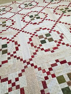 a quilt is laying on the floor with red, green and white squares all over it