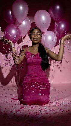 a woman in a pink dress holding balloons