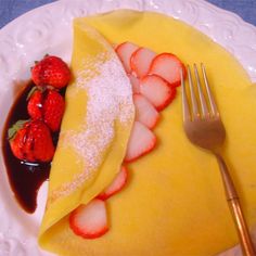 a plate with strawberries and powdered sugar on it, next to a fork