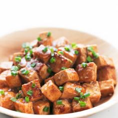 a bowl filled with tofu and green onions