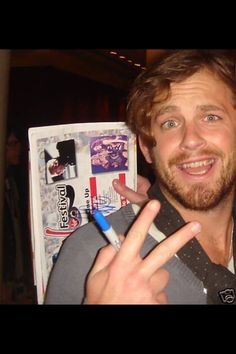 a man is holding up his peace sign in front of an open magazine and pointing at the camera