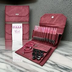 an assortment of sewing tools in a case on a marble counter top next to a package of thread and needles