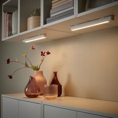 two vases with flowers are sitting on a shelf