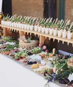 an assortment of food is displayed on a long table with cups and sticks sticking out of them