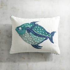 a decorative pillow with a blue fish on the front and white back, sitting on a wall