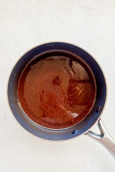 a pan filled with soup sitting on top of a white counter next to a knife