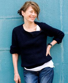 a smiling woman leaning against a blue wall