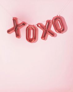 red foil balloons spelling the word tokyo hanging from a string on a pink background with white lettering