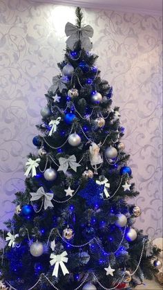 a blue christmas tree with white and silver ornaments