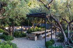 a wooden bench sitting under a canopy next to trees