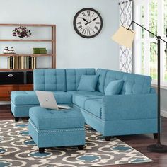 a living room with a blue sectional couch and ottoman in front of a clock on the wall