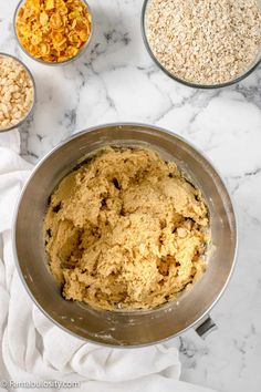 ingredients to make oatmeal cookies in bowls on a white marble counter top