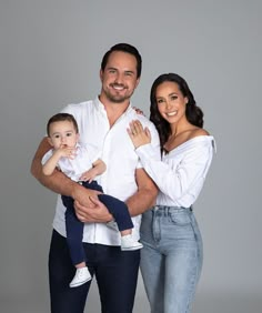 a man, woman and baby posing for a photo in front of a gray background