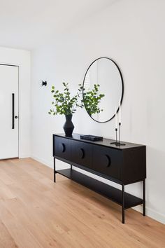 a black dresser and mirror in a white room