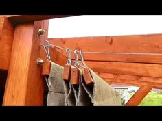 two pieces of cloth hanging on a clothes line with hooks attached to the side of a wooden structure