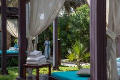 a woman is standing in the middle of an outdoor area with white curtains and blue cushions