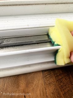 someone is cleaning the window sill with a sponge