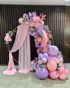 a balloon arch with balloons and flowers on it