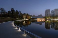 a large body of water surrounded by tall buildings at night with lights on the sides