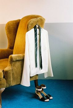 a pair of high heeled shoes sitting on top of a chair next to a white shirt and tie