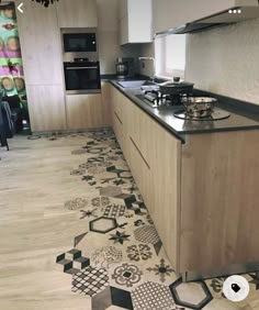 a kitchen with black and white tiles on the floor, counter tops and cabinets in it