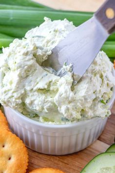 a white bowl filled with cucumber dip surrounded by crackers and celery