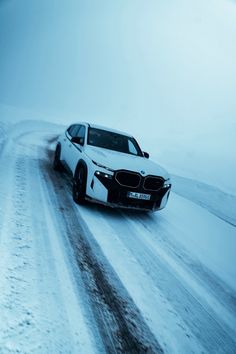 a white car driving down a snow covered road