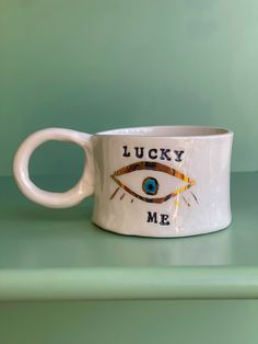 a coffee cup with an eye on it that says lucky m & m and the words