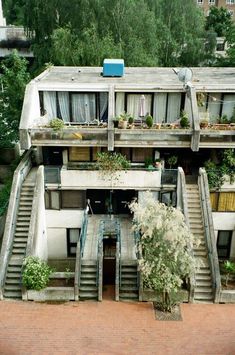 an apartment building with plants growing on the balconies and stairs leading up to it