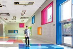 a man standing in the middle of a room with colorful walls and floor tiles on it