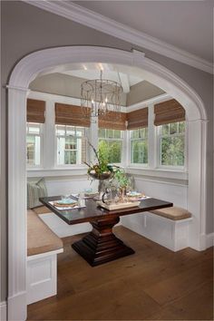 an archway leading into a dining room with a table and bench in the center area