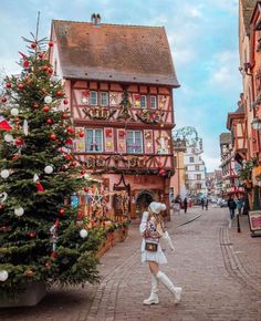 a woman is walking down the street with a christmas tree in front of her,