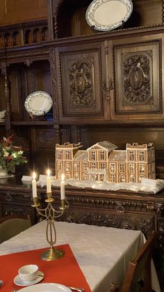 a dining room table is set with place settings and candles in front of the china cabinet