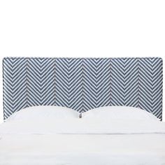 an upholstered headboard with white sheets and blue herringbones on it