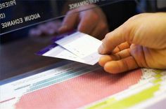 a person is holding up two tickets in front of a computer screen with japanese writing on it