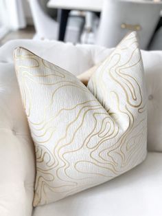 a close up of a pillow on a white couch in a room with furniture and accessories