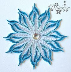 a blue and white paper flower on a white wall