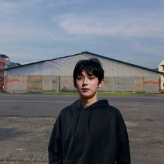 a young man standing in the middle of an empty parking lot next to a building