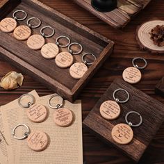 six wooden key chains with engraved words on them, sitting next to an open book