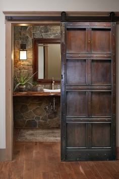 an open door leading to a bathroom with stone wall and wood flooring on the walls