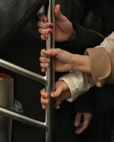 two hands holding onto the bars of a metal railing on a subway train or bus